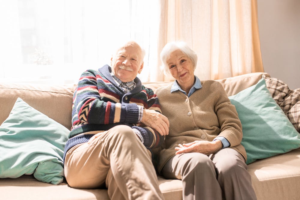 smiling-senior-couple-posing-sofa-sunlight