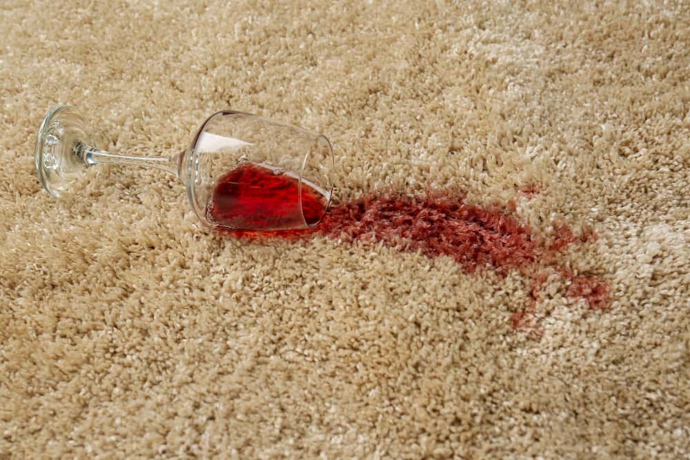 overturned glass and spilled red wine on soft carpet